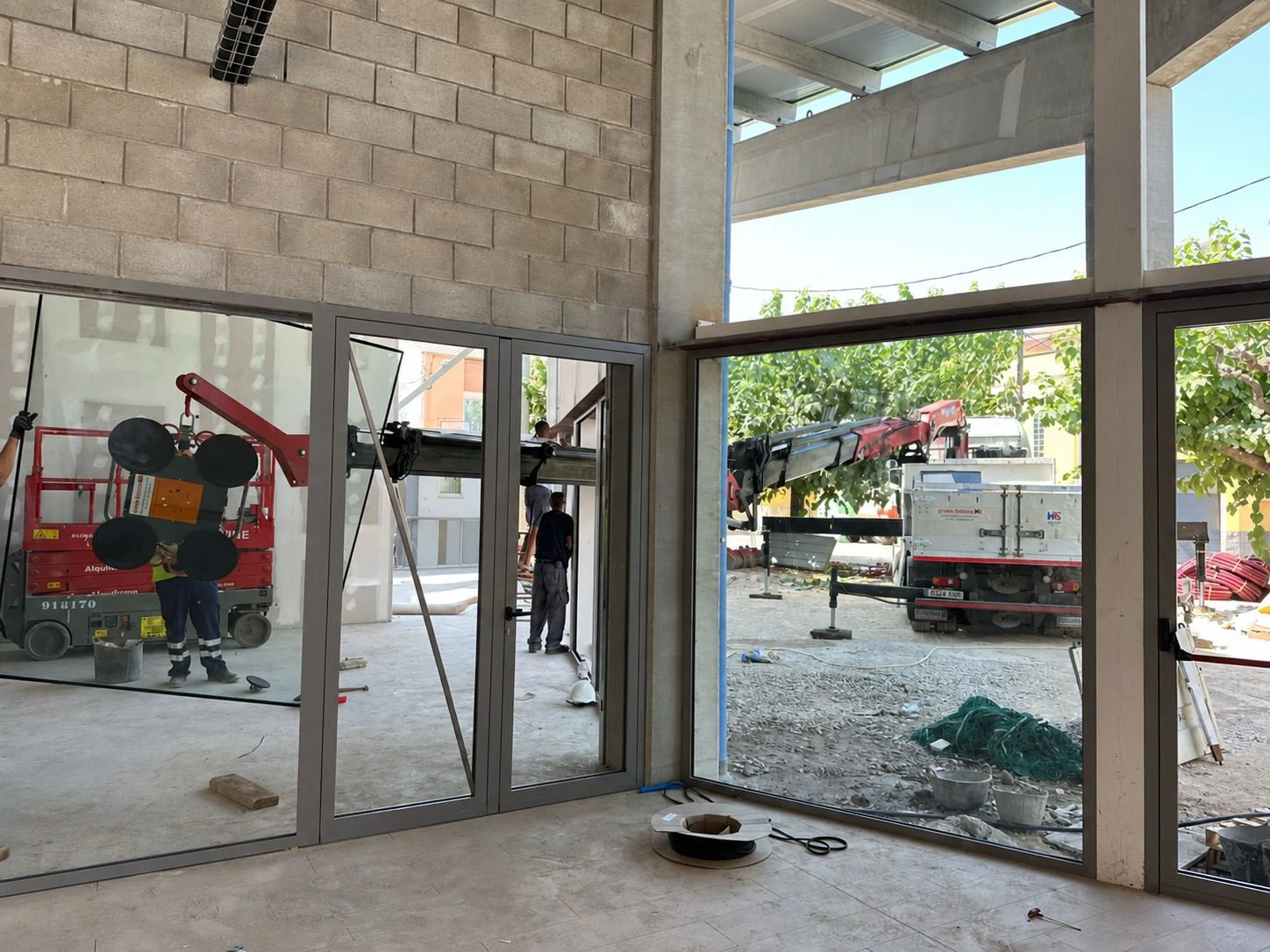 Operario de Solano manejando un panel de vidrio con la ventosa de vacío durante el montaje de un cerramiento en obra