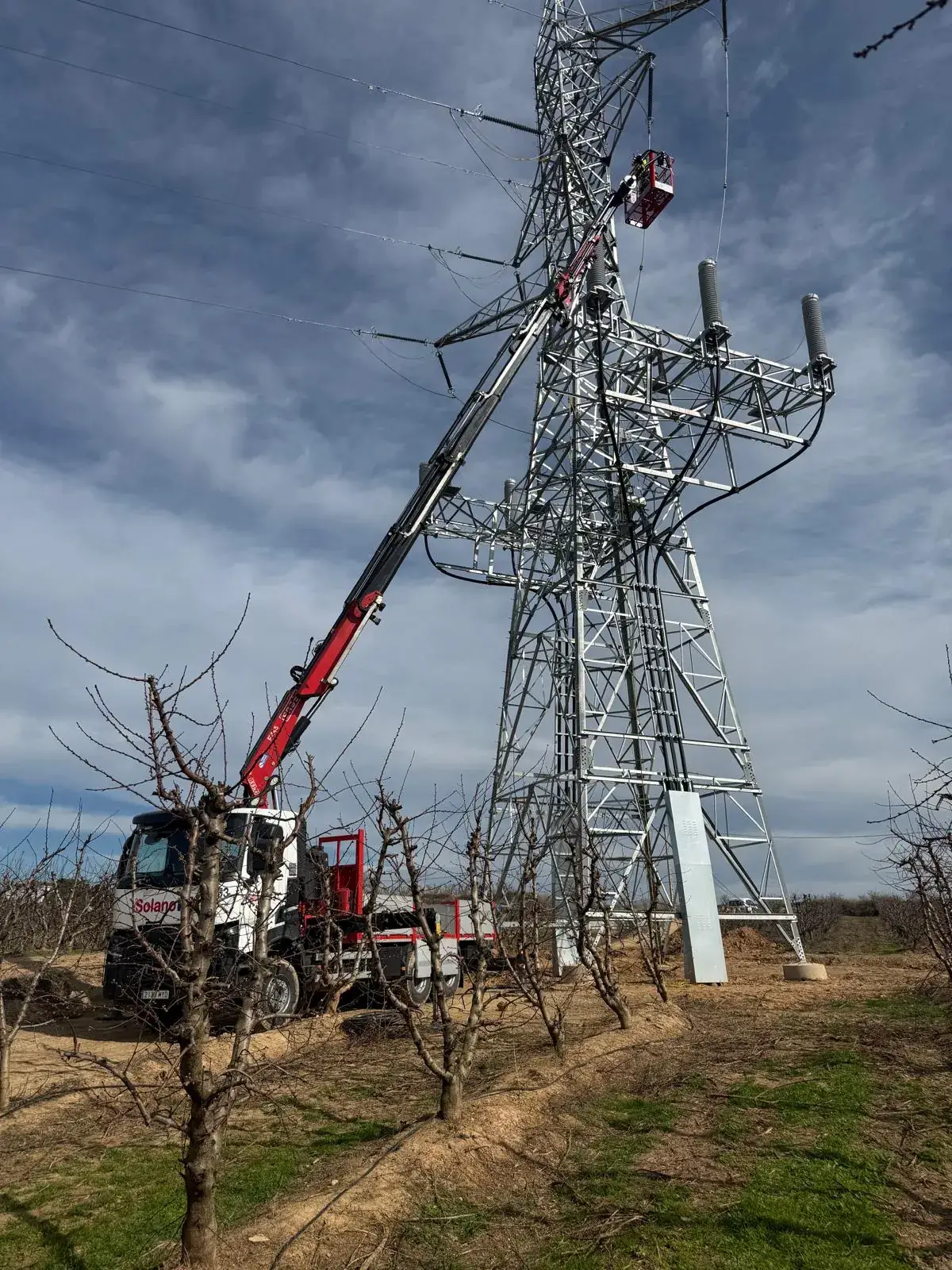 Camión grúa de Solano con la cesta trabajando en lo alto de una torre de alta tensión