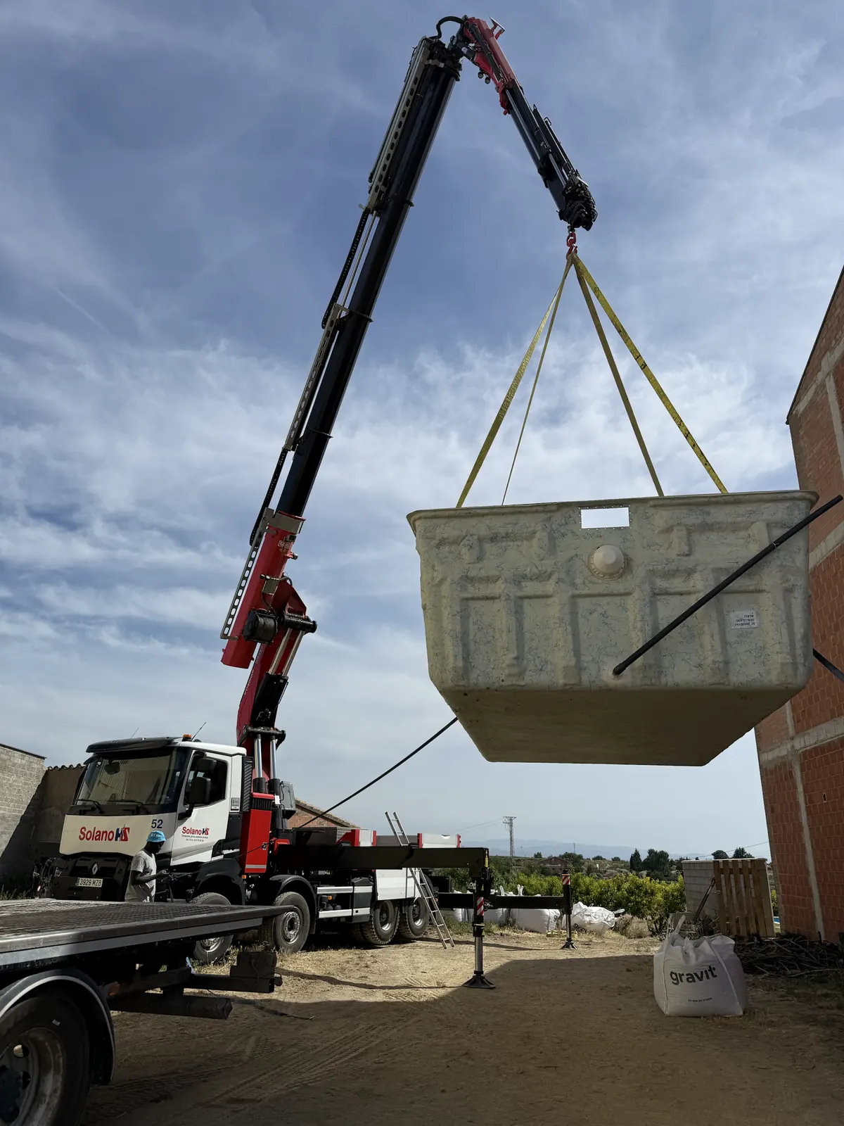 Camión grúa colocando una piscina prefabricada, suspendida con eslingas