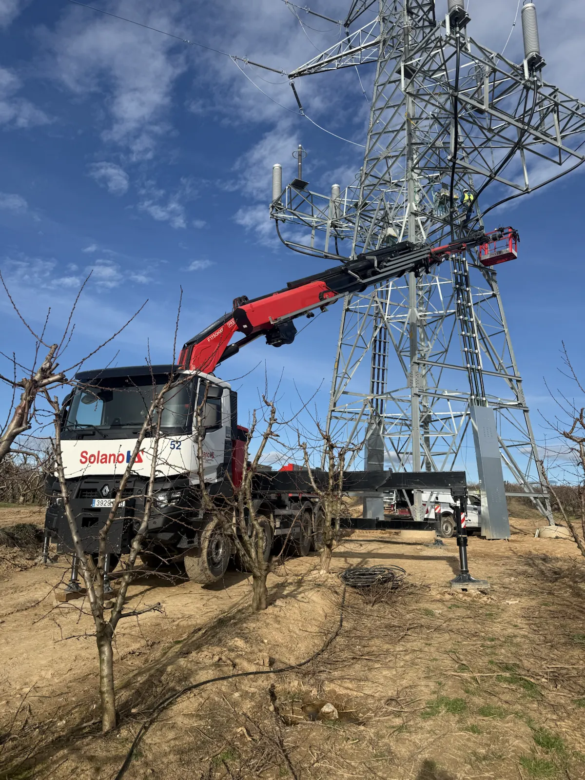 Camión grúa trabajando junto a torre eléctrica