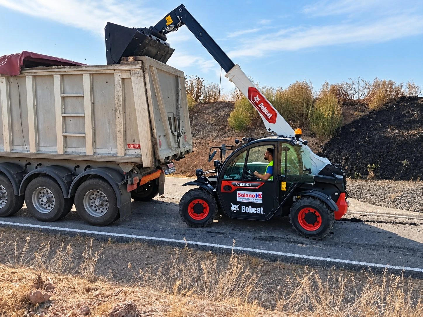 Manipulador telescópico Bobcat de Solano trasvasando la carga a un volquete en carretera