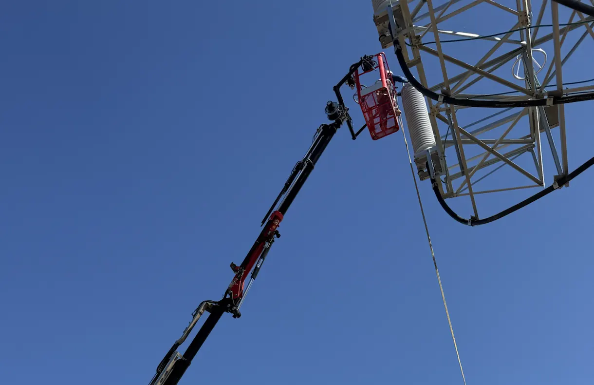La cesta en el extremo de la pluma, trabajando en lo alto de una torre de alta tensión