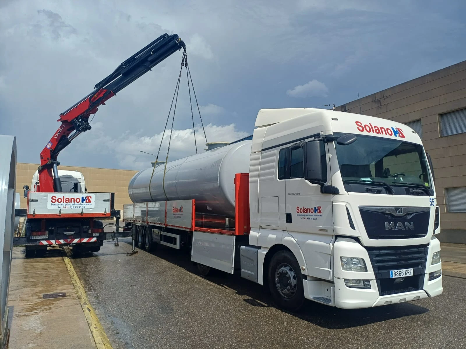 Tractora de Solano con un depósito de acero inoxidable sobre la plataforma, cargado con la ayuda de un camión grúa